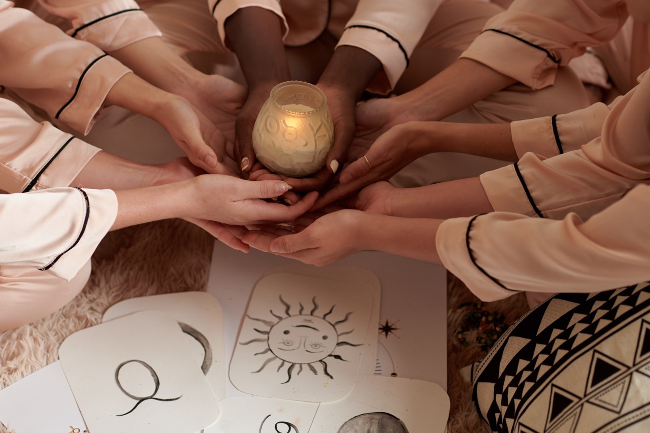 A warmly lit room with candles and lamps glowing against a dark winter window
